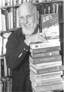 black and white photograph of James Loewen holding a stack of books he has authored