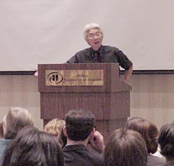 photograph of Ronald Takaki addressing a crowd from the podium of the Hilton Hotel